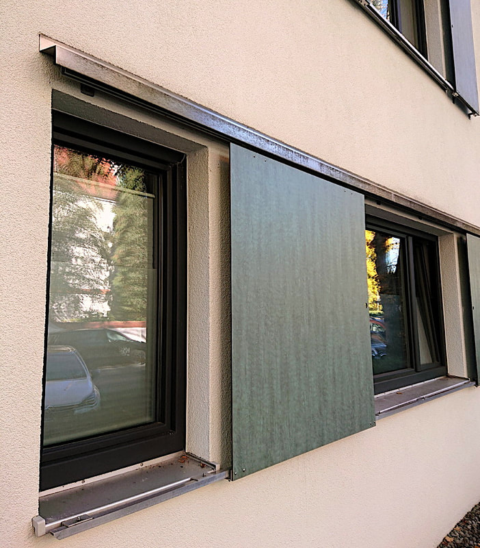 Window-shutters with weather-proofed stained plywood panels on stainless steel rails; Munich/Germany, 